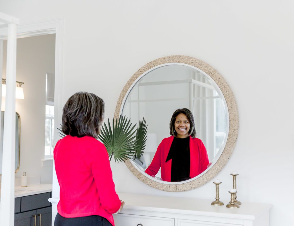 Real Estate Advisor smiles into a round mirror.