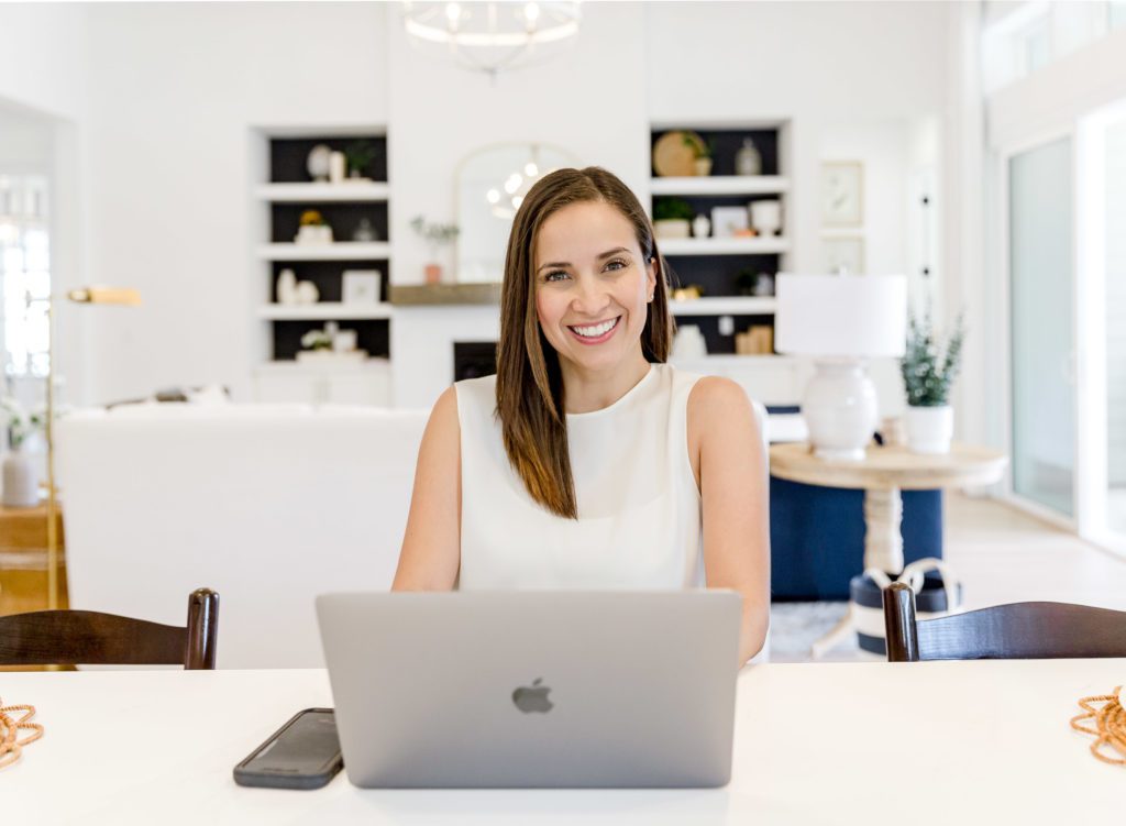 Professional woman in white blouse in front of Apple laptop.